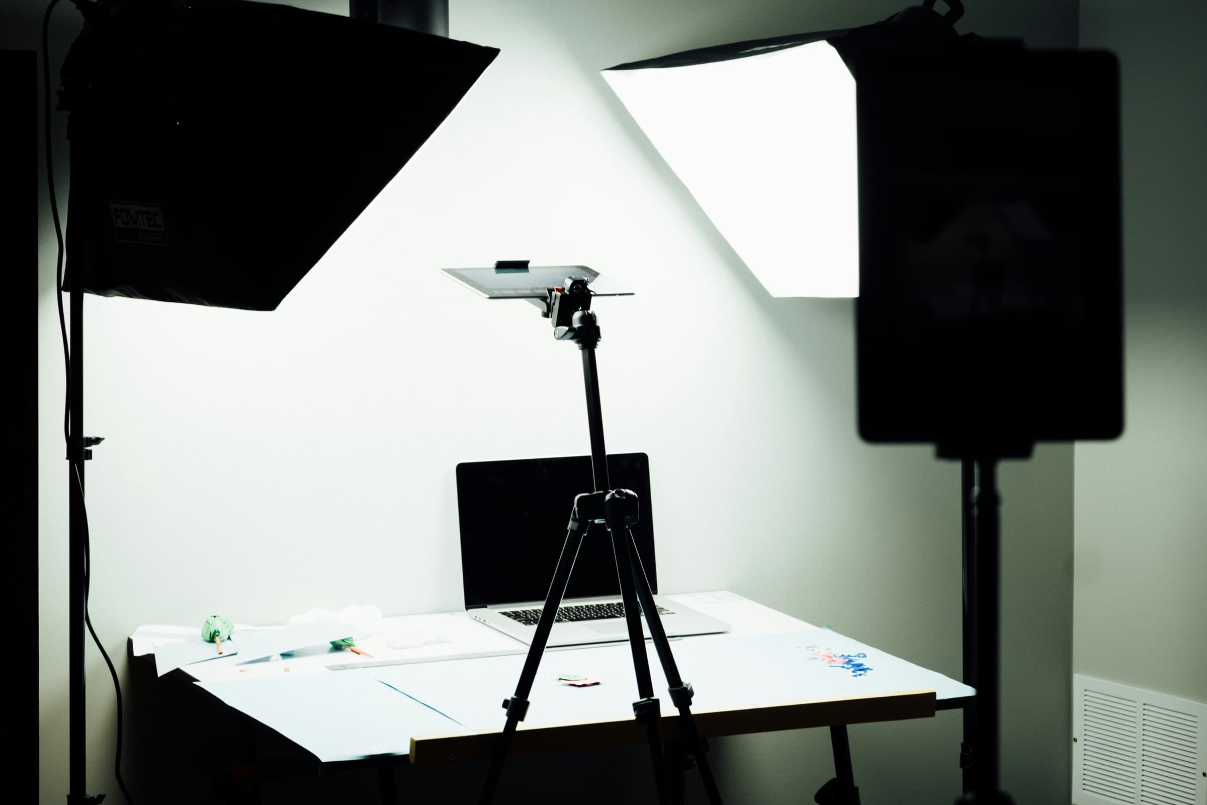 Mesa de criação de conteúdo com notebook, tripé e iluminação para fotos de produto